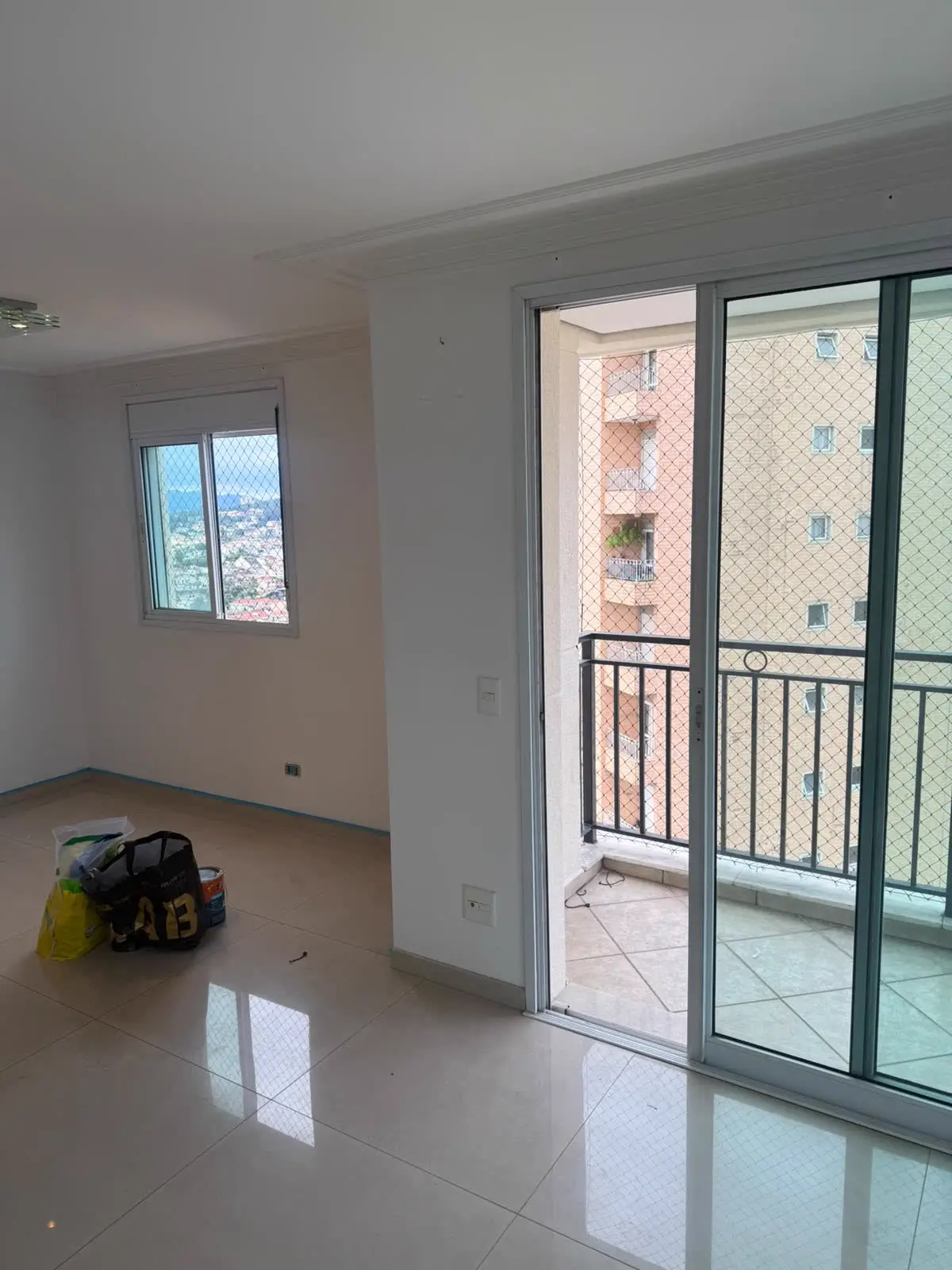 Sala de apartamento com sacada e janela protegidas por rede